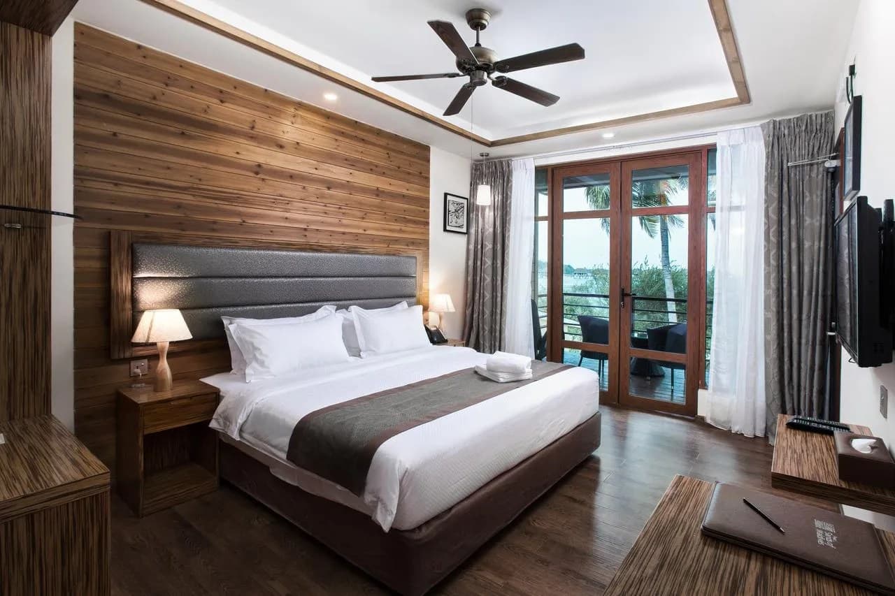 Wood-panelled bedroom at Pearl Sands of Maldives with a balcony facing palms and the sea